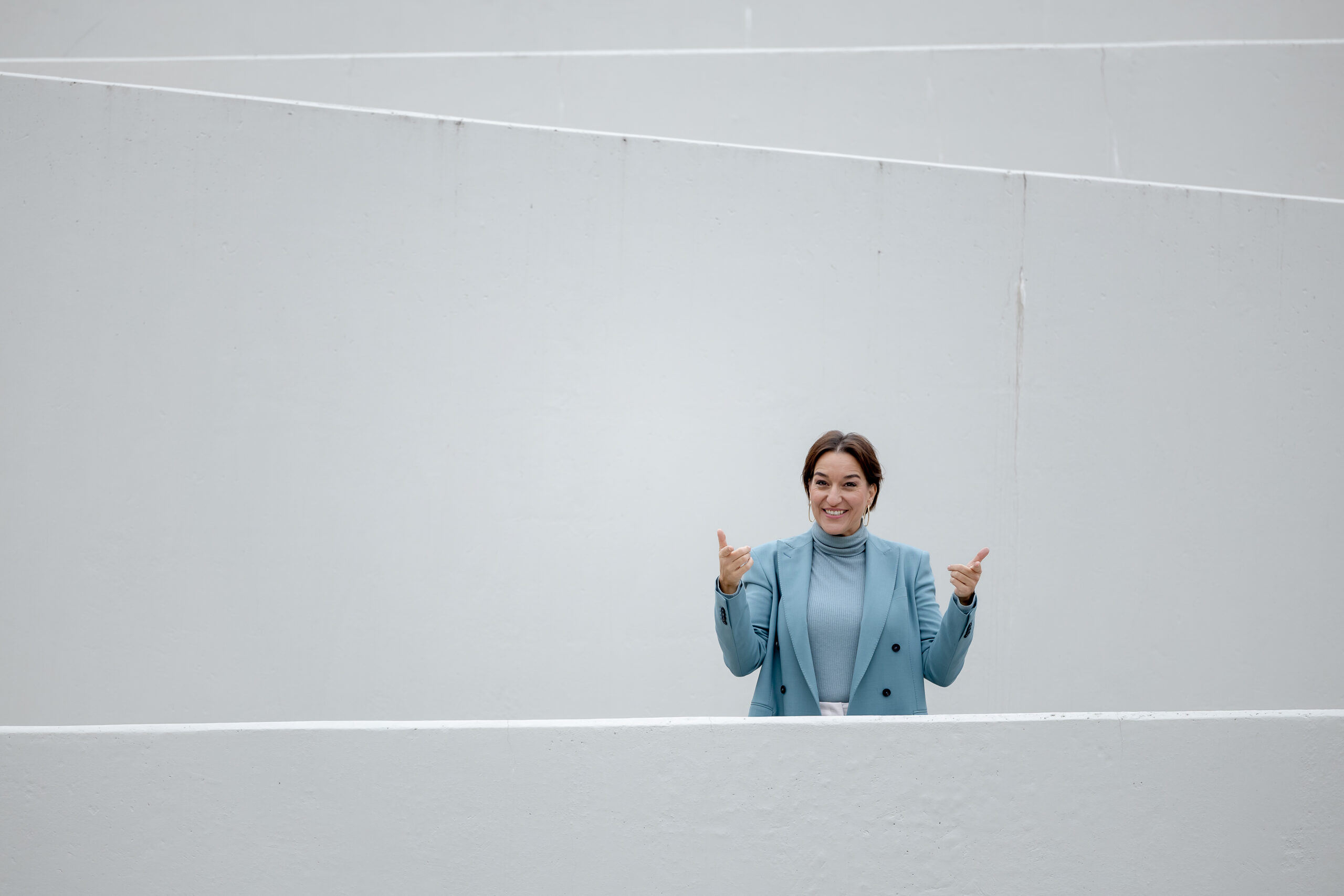 Katinka Riemann hebt hinter einer weißen Brüstung beide Hände