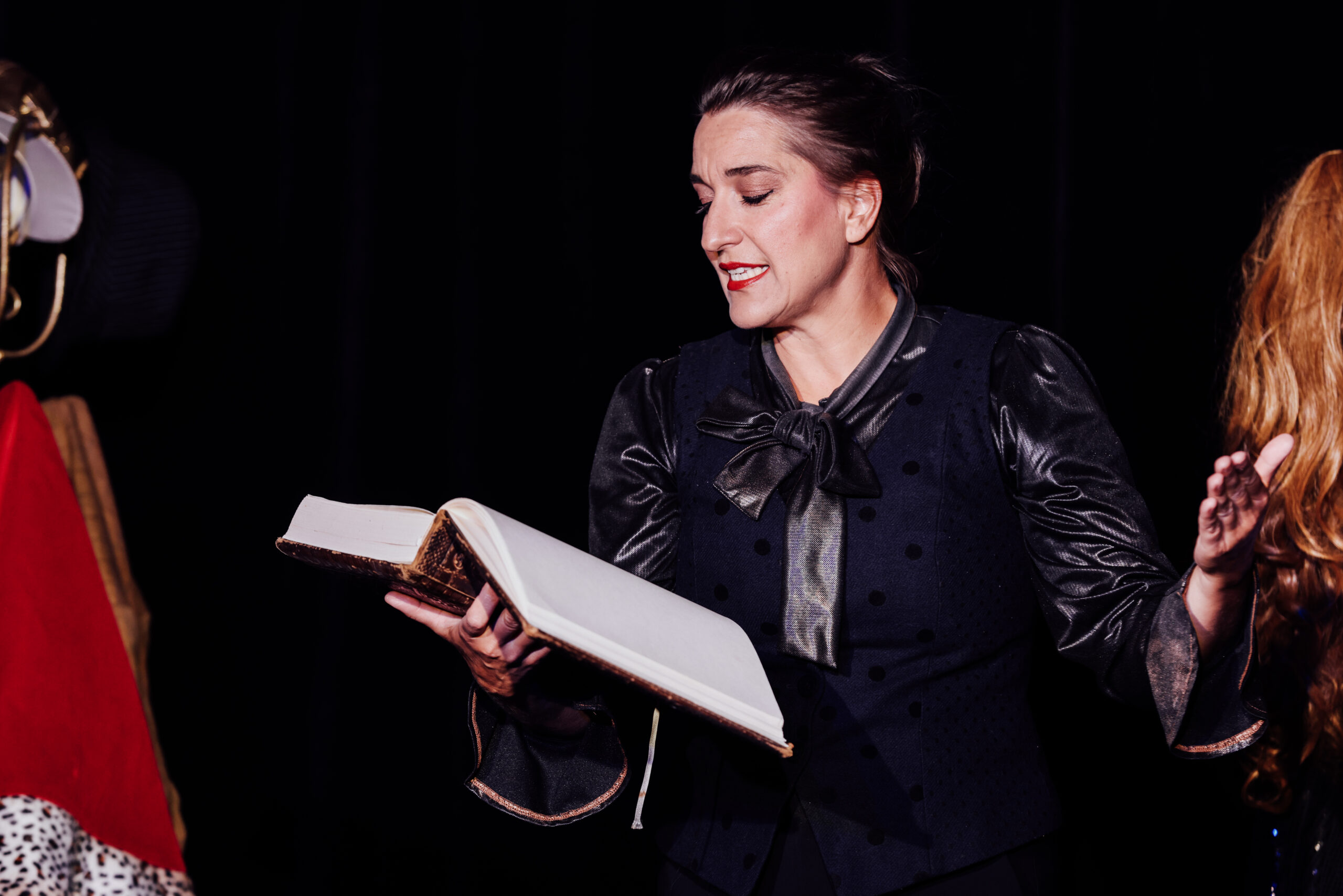 Katinka Riemann in „Froschsalat“ liest auf der Bühne aus einem großen Buch vor