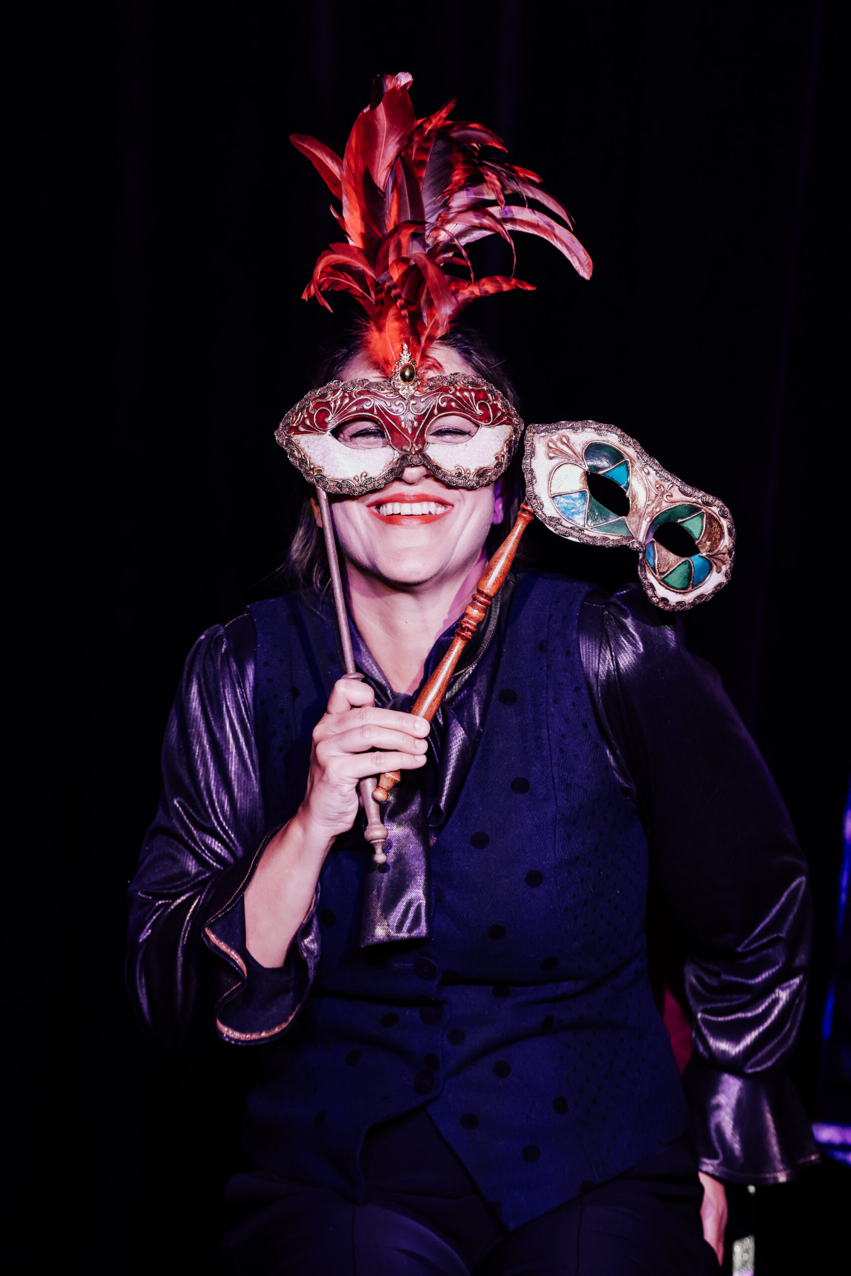 Katinka Riemann in „Froschsalat“ hält zwei venezianische Masken vor ihr Gesicht