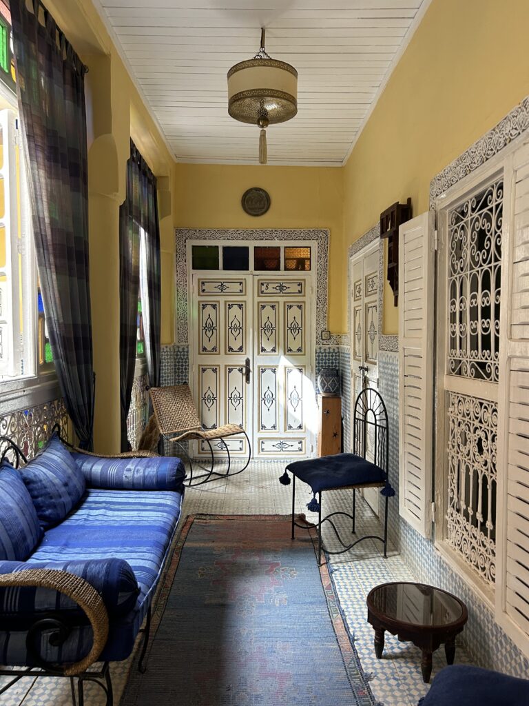Langer Flur in einem Riad in Marrakesch mit blauem Sofa, Holzgittern und Laterne
