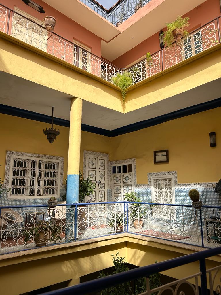 Innenhof eines Riads in Marrakesch mit gelben Wänden und umlaufender Galerie
