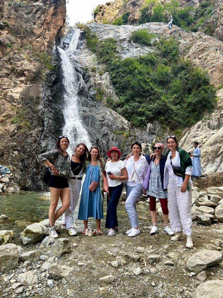 Gruppe von Frauen vor einem Wasserfall in felsiger Berglandschaft