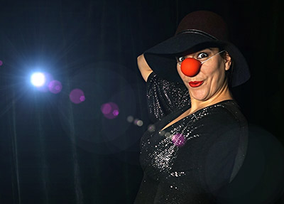 Katinka Riemann als Clownin mit roter Nase und Hut im Bühnenlicht