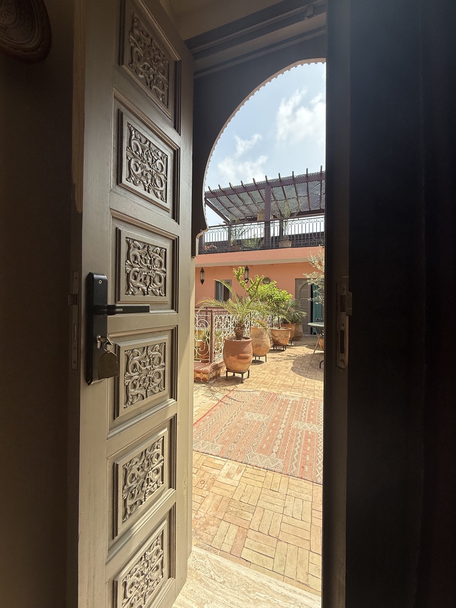Blick durch eine geschnitzte Tür in den Innenhof eines Riads in Marrakesch